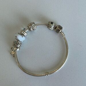 Pandora bracelet with 5 charms and 1 spacer with cross.